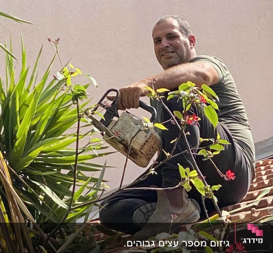 אדם גוזם צמחים עם מסור על גג